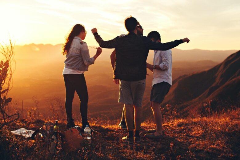 four-person-standing-at-top-of-grassy-mountain